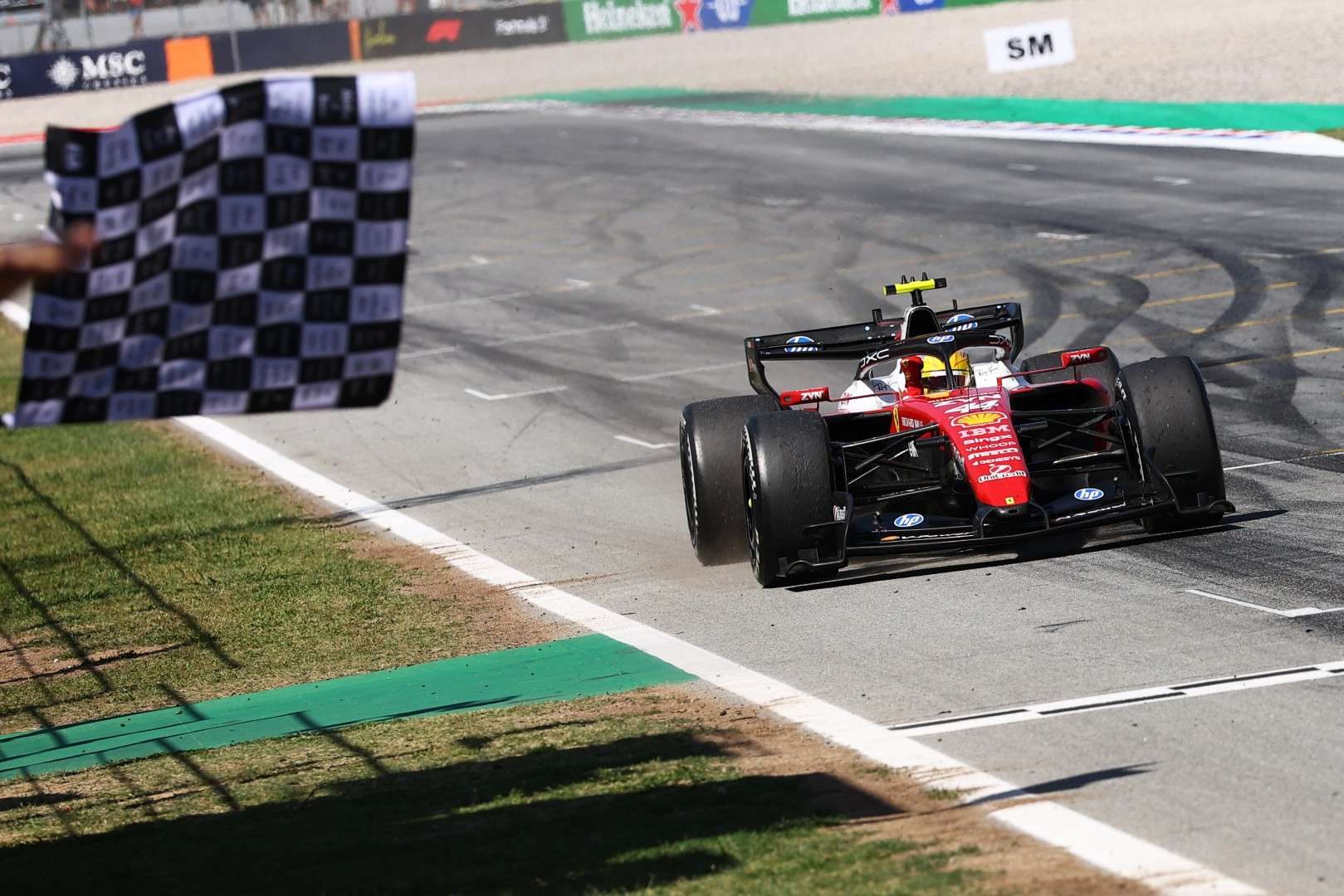 Lewis Hamilton crossing the finish line in his Ferrari after executing a successful three-stop strategy at the Barcelona Grand Prix.
