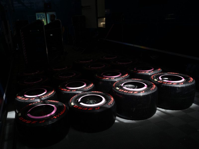 Multiple sets of Pirelli Formula 1 racing tires prepared in the garage for a three-stop strategy.