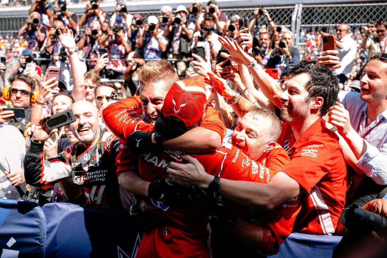 Scuderia Ferrari team and mechanics celebrating a podium finish secured by a brilliant three-stop strategy.