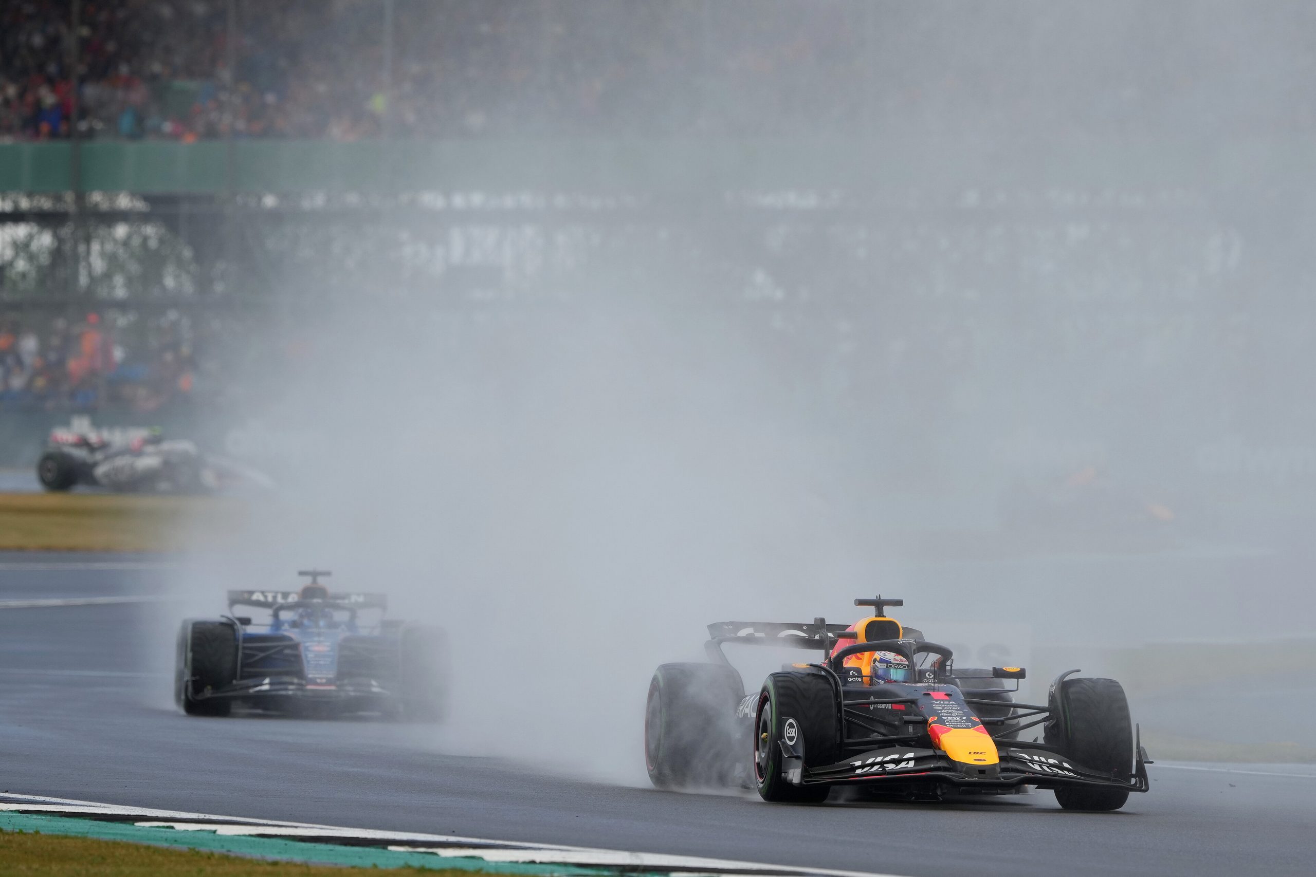 Red Bull Formula 1 car leading through wet conditions at Silverstone.