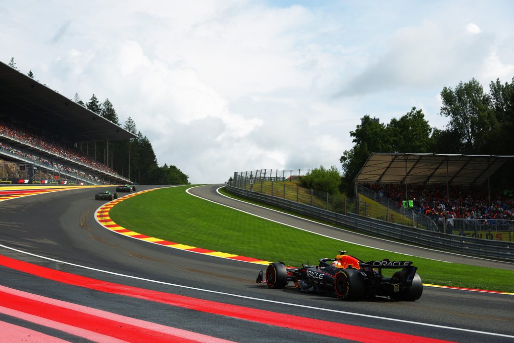 Red Bull Formula 1 car climbing Eau Rouge and Raidillon at Spa‑Francorchamps with spectators in grandstands.